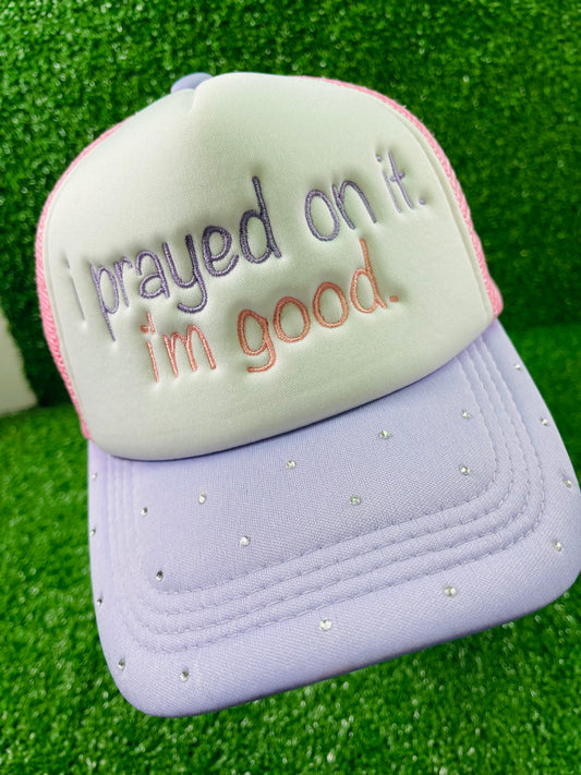 Custom embroidered pink and purple trucker hat with the phrase I prayed on it. I'm good. stitched on the front in purple and pink thread. The lavender brim is embellished with small rhinestones, adding a sparkly touch. 
