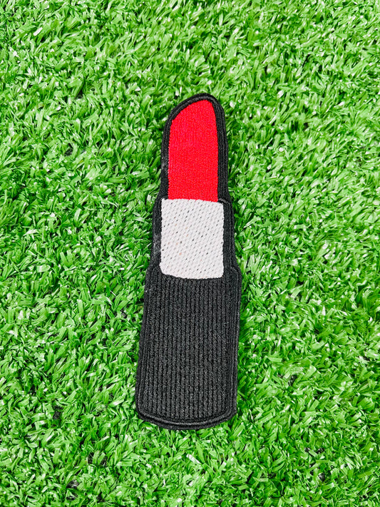 Lipstick-shaped object with red top and gray bottom on a green grass background