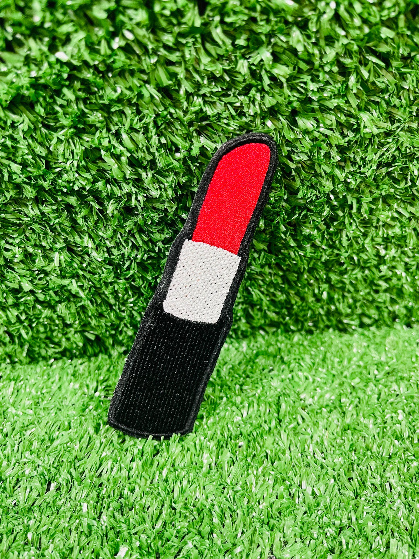 Black and red golf club head cover on green grass