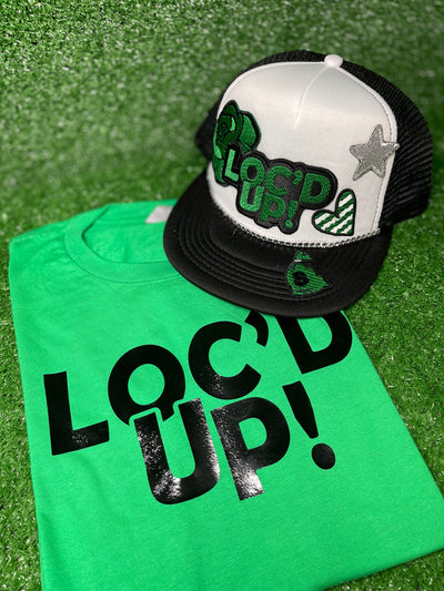 White & Black trucker hat with the text 'Loc’d Up' embroidered in bold black and green letters with other accent patches. The hat features a classic mesh back and adjustable snap closure, perfect for showcasing your locs with style.