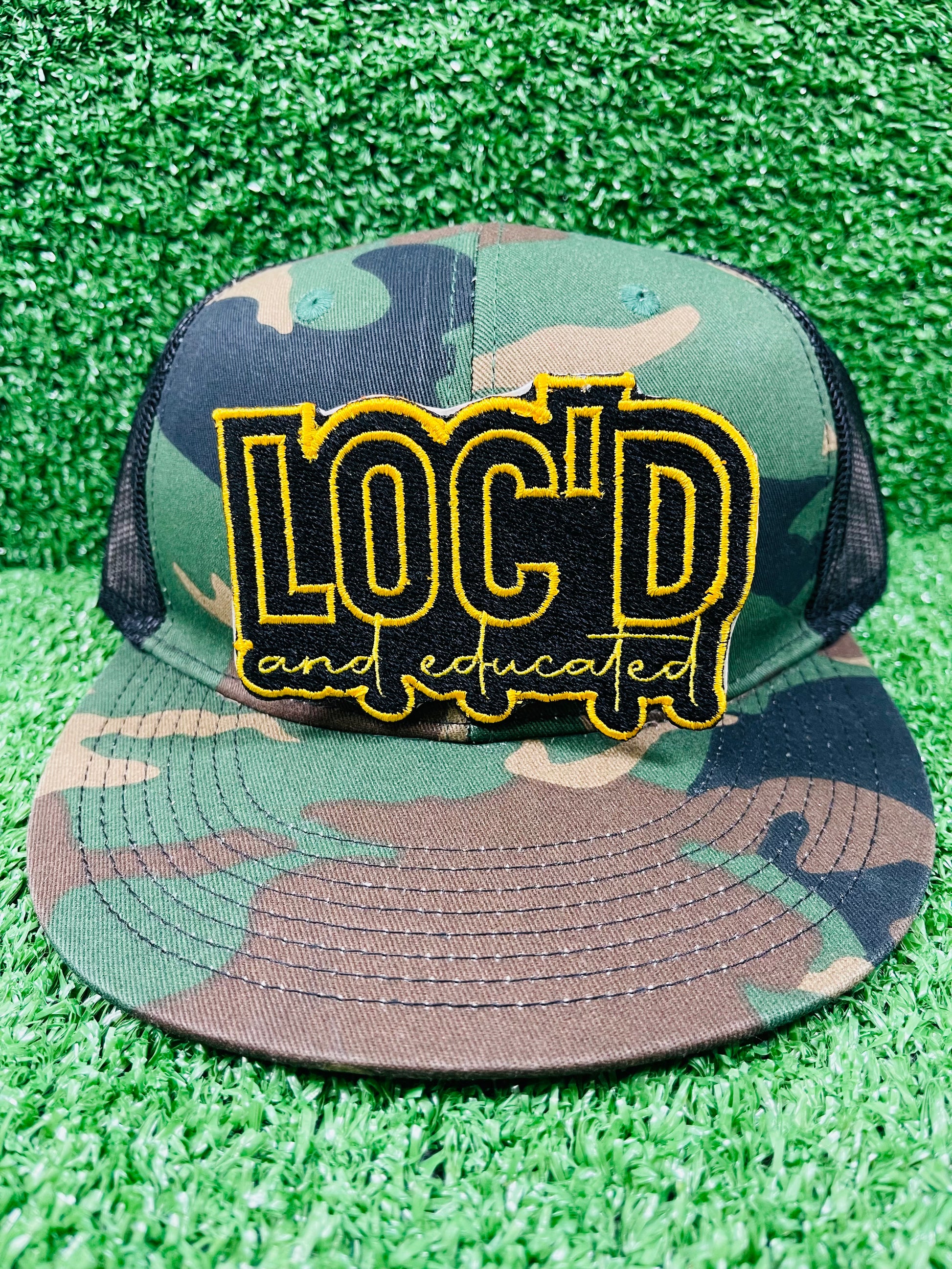 Camouflage cap with 'LOC'D and Educated' patch.