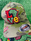 Colorful embroidered iron on patch spelling LOVE with the African continent as the "O" in red, yellow, green and black tones, bold and vibrant design.