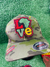 Colorful embroidered iron on patch spelling LOVE with the African continent as the "O" in red, yellow, green and black tones, bold and vibrant design.