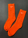 Orange Nike socks embellished with sparkling rhinestones, adding a touch of bling and style.  The socks feature a bold orange color with rhinestones carefully placed for a dazzling effect, perfect for elevating any sneaker look.