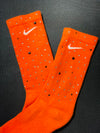 Orange Nike socks embellished with sparkling rhinestones, adding a touch of bling and style.  The socks feature a bold orange color with rhinestones carefully placed for a dazzling effect, perfect for elevating any sneaker look.