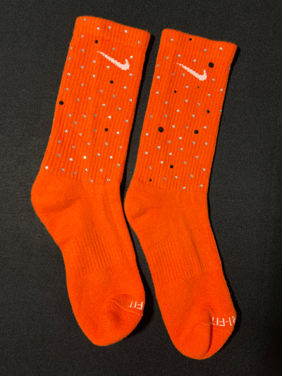 Orange Nike socks embellished with sparkling rhinestones, adding a touch of bling and style.  The socks feature a bold orange color with rhinestones carefully placed for a dazzling effect, perfect for elevating any sneaker look.