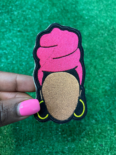 Embroidered patch featuring a faceless Nubian queen with a vibrant pink headwrap and yellow hoop earrings on a black background.