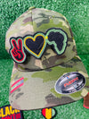 A colorful, embroidered patch featuring a red peace sign a yellow heart, and the silhouette of Africa in green and black. The design symbolizes unity, love, and pride in African heritage.