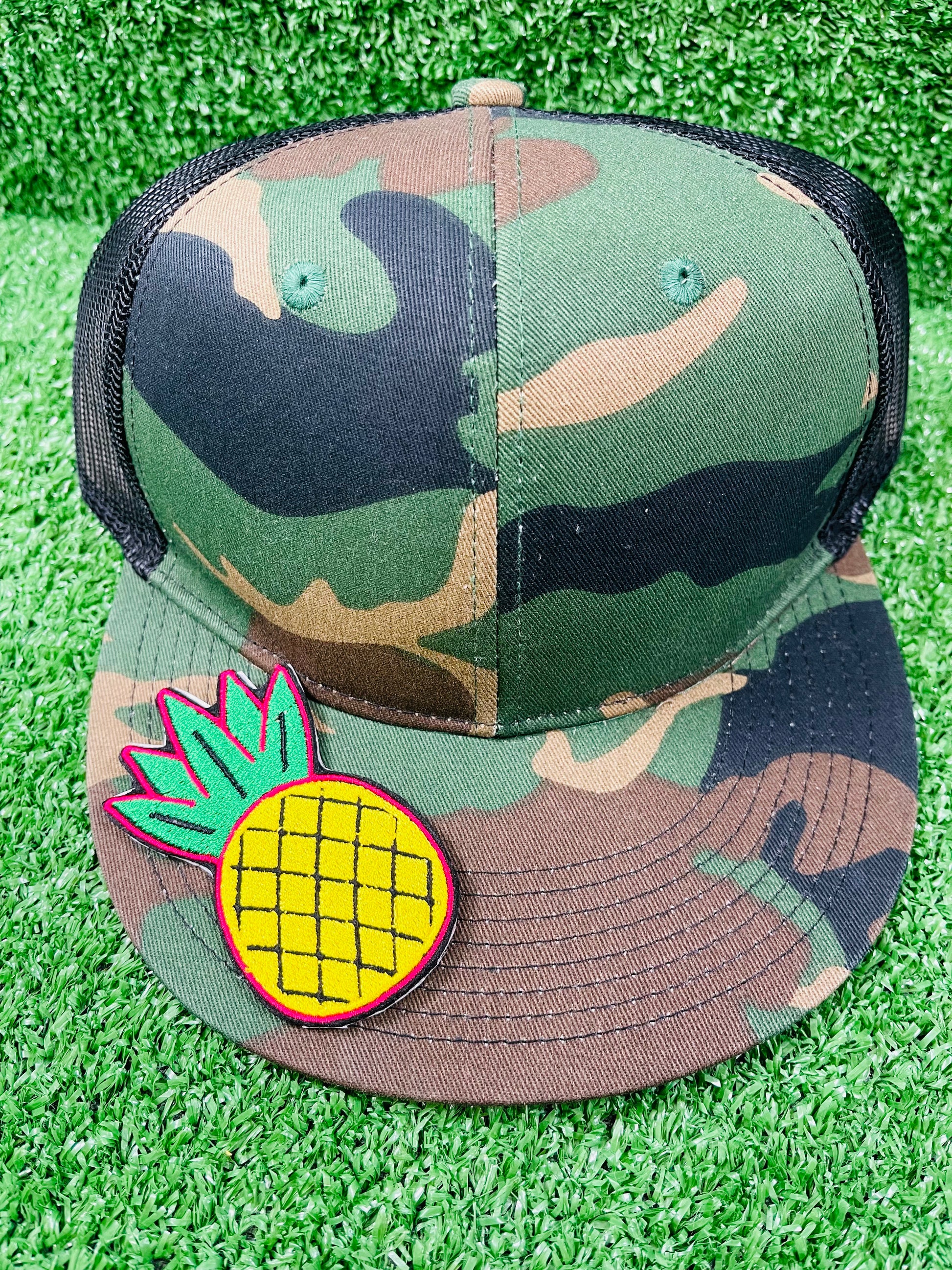 Camouflage cap with a pineapple patch on a grass background