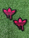 Detailed view of a pink Adidas iron-on patch with the classic trefoil logo and three stripes, perfect for adding a stylish, personalized touch to clothing.