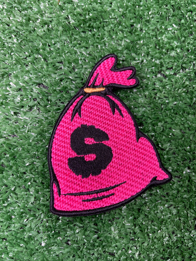 Embroidered patch depicting a money bag with a dollar sign, featuring pink, black and gold colors for a bold and eye-catching design.