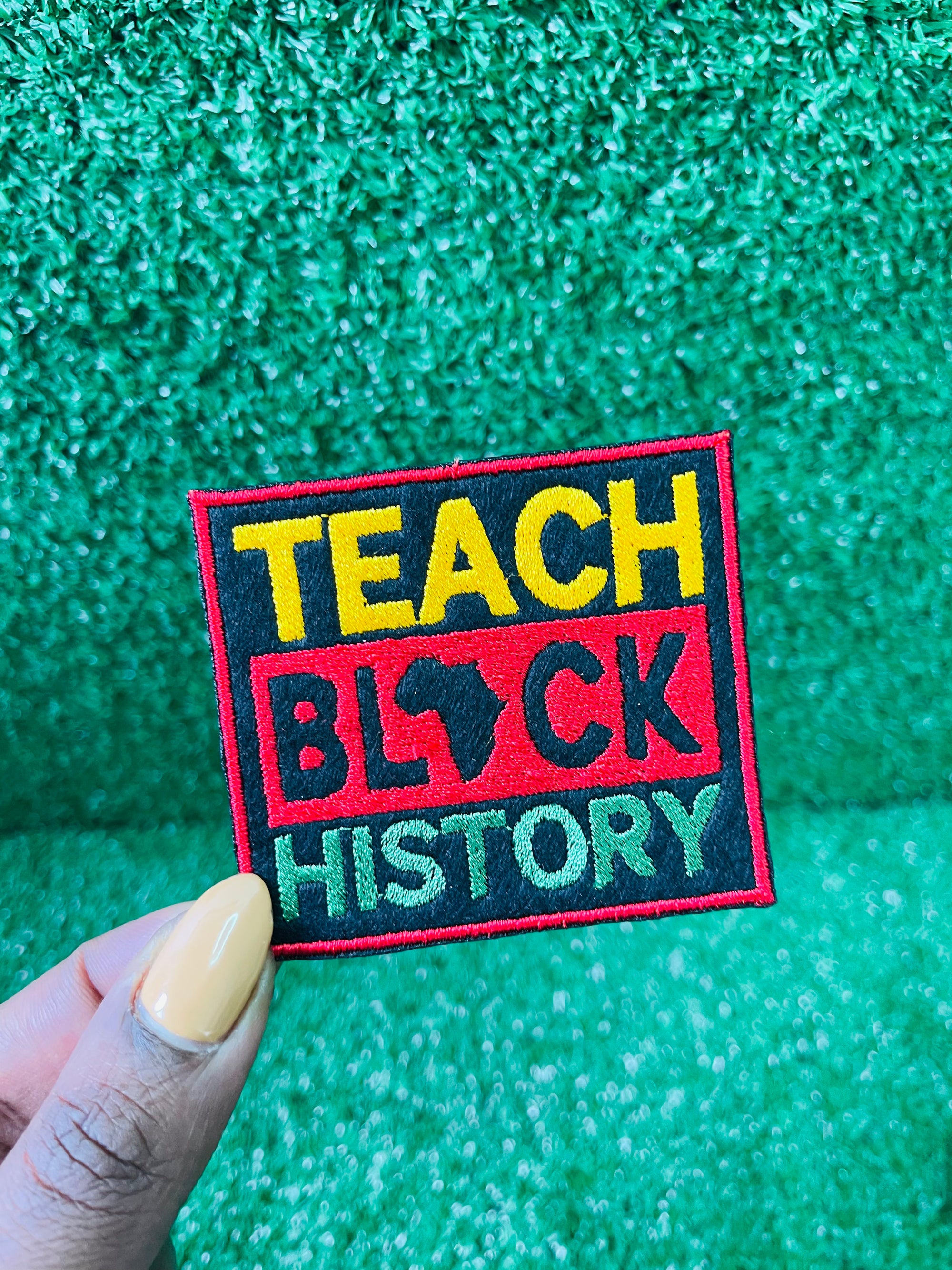 A vibrant, rectangular embroidered patch with the bold words Teach Black History in yellow, red, and green. The design features the outline of Africa within the word Black symbolizing pride, education, and cultural heritage. 