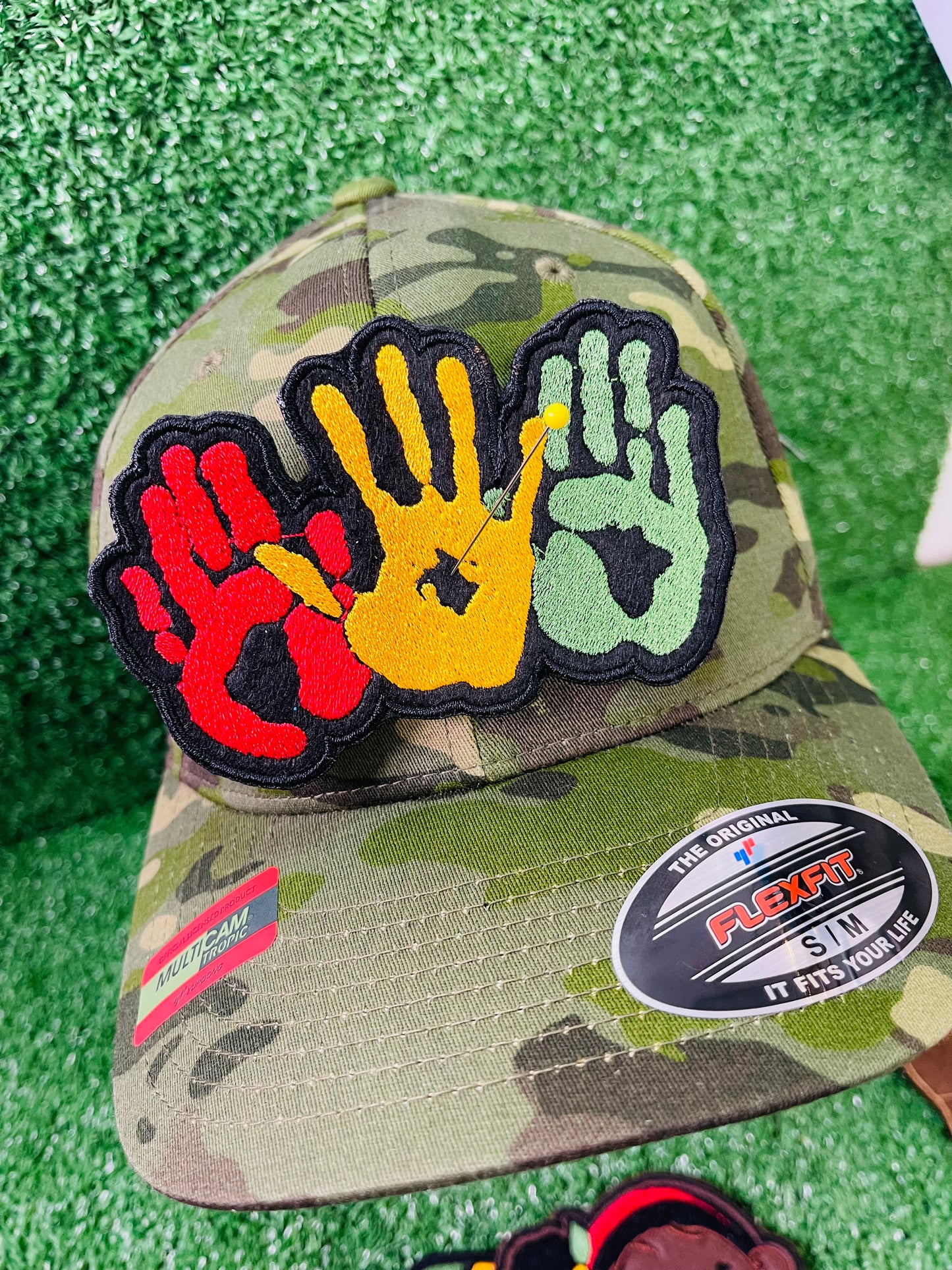 A vibrant embroidered patch featuring three overlapping handprints in red, yellow, green, symbolizing unity. pride, and heritage. The patch has a bold black outline that enhances the striking design. Perfect for celebrating Black culture and adding a meaningful touch to clothing or accessories. 