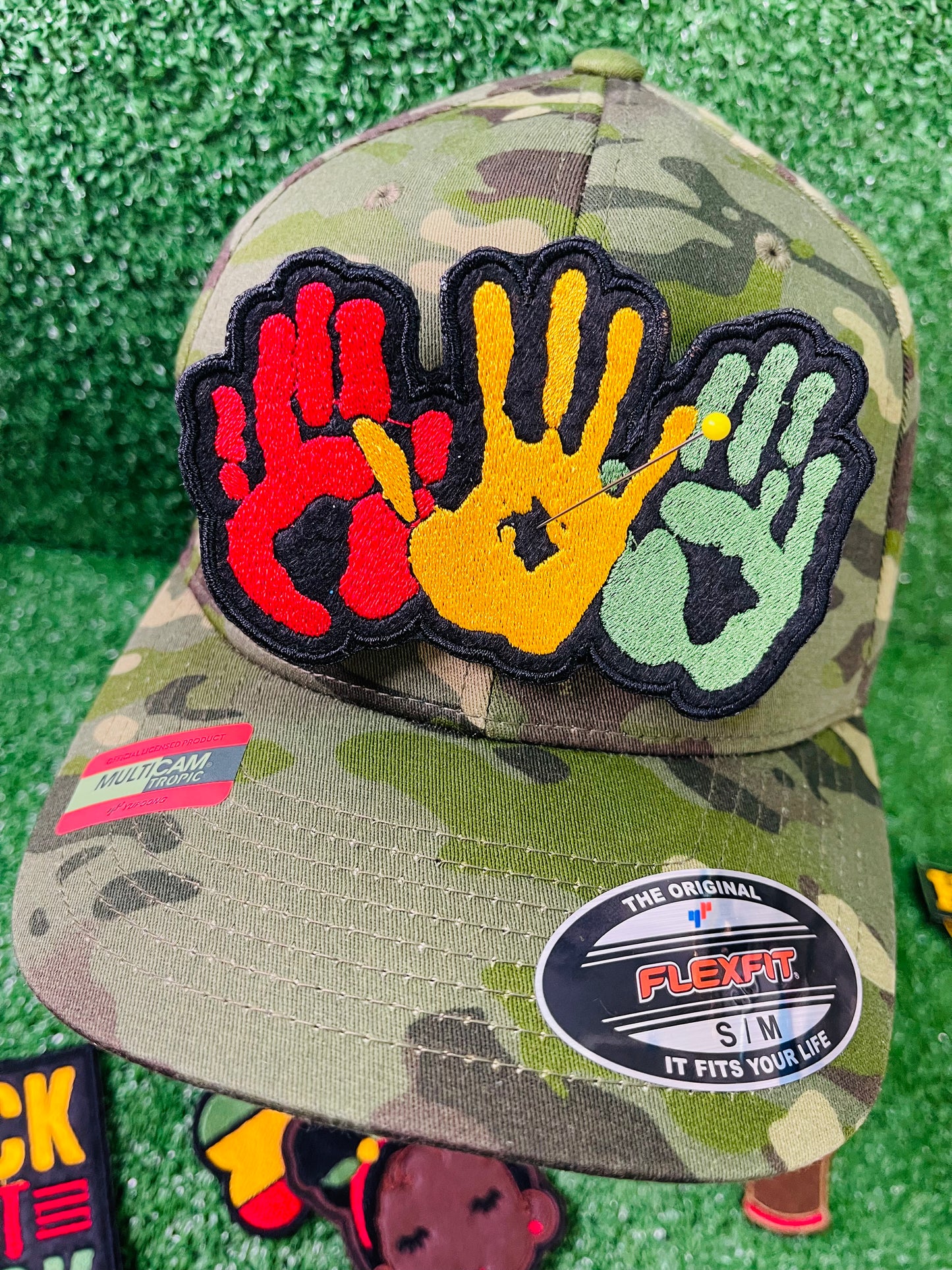 A vibrant embroidered patch featuring three overlapping handprints in red, yellow, green, symbolizing unity. pride, and heritage. The patch has a bold black outline that enhances the striking design. Perfect for celebrating Black culture and adding a meaningful touch to clothing or accessories. 