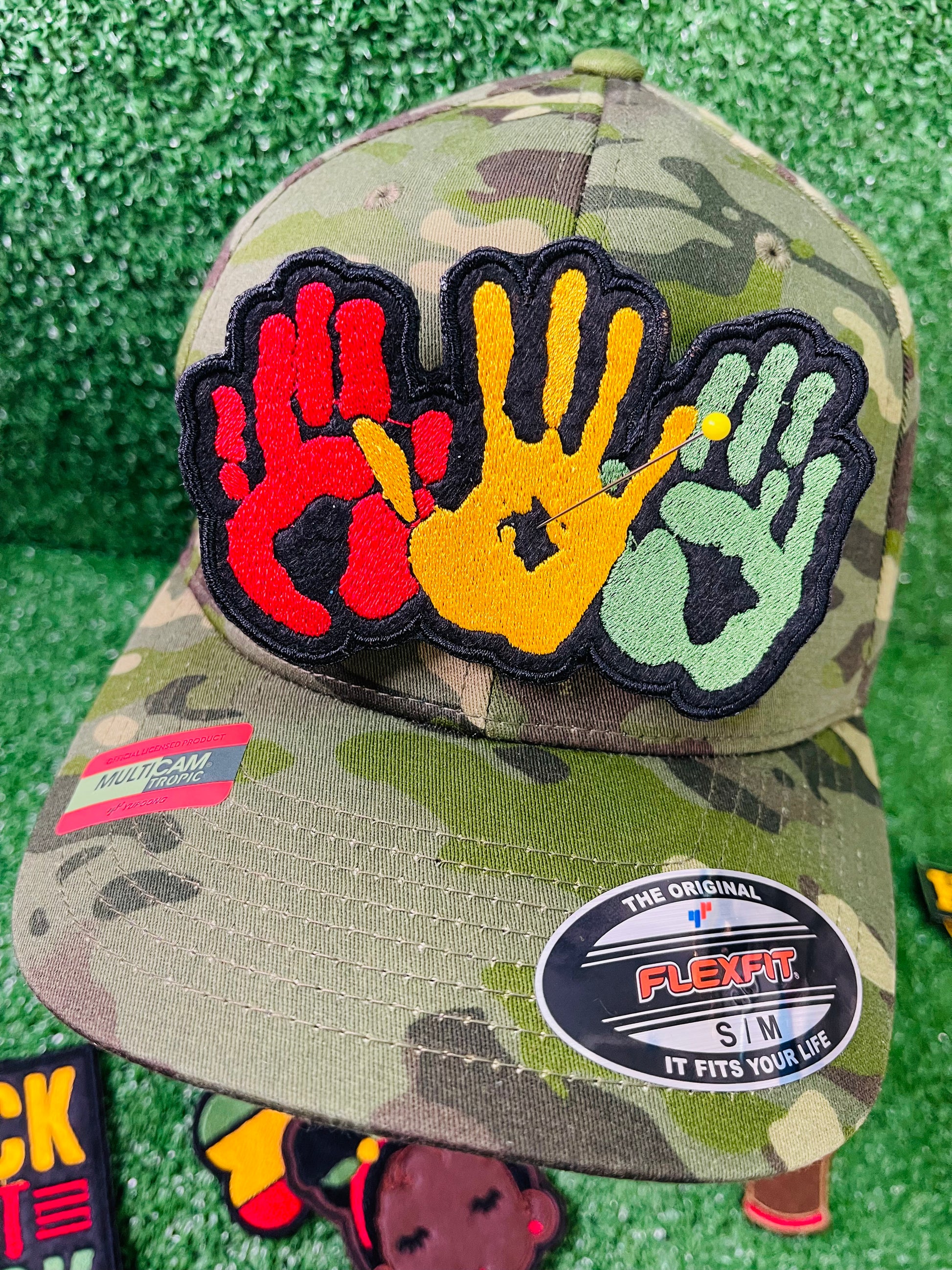 A vibrant embroidered patch featuring three overlapping handprints in red, yellow, green, symbolizing unity. pride, and heritage. The patch has a bold black outline that enhances the striking design. Perfect for celebrating Black culture and adding a meaningful touch to clothing or accessories. 